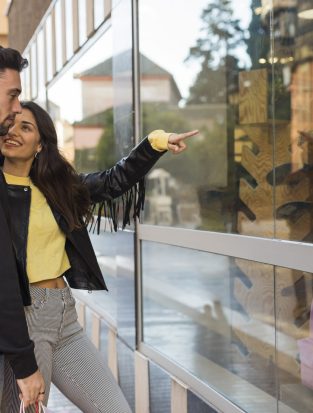 happy-woman-hugging-showing-shop-window-young-man