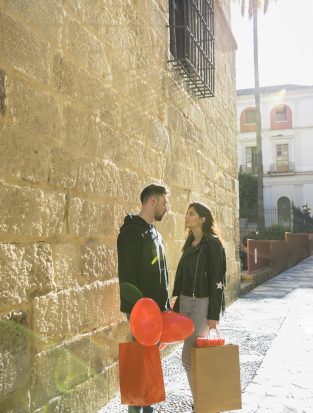 young-guy-with-packets-balloons-near-lady-street